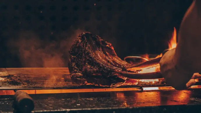 person cooking meat on grill